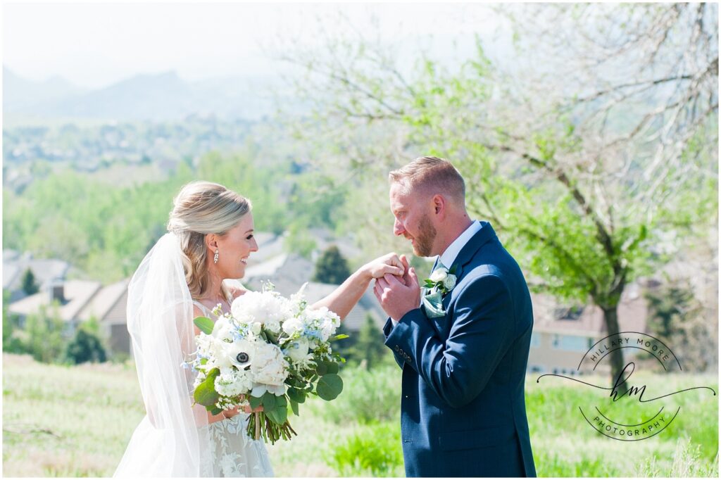 Groom kissing the hand of the bride as she is smiling.