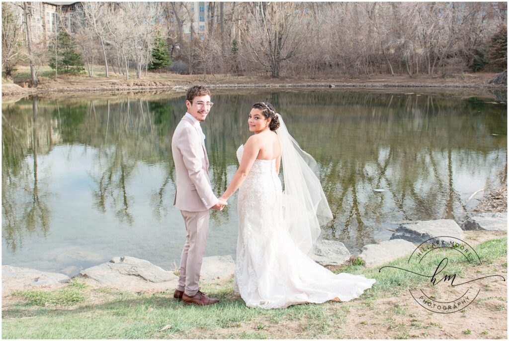 Bride and groom holding hands in front of a pond