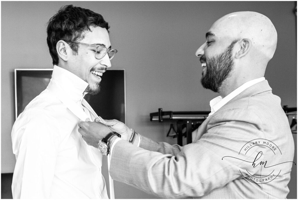 Best man helping the groom tie his tie.