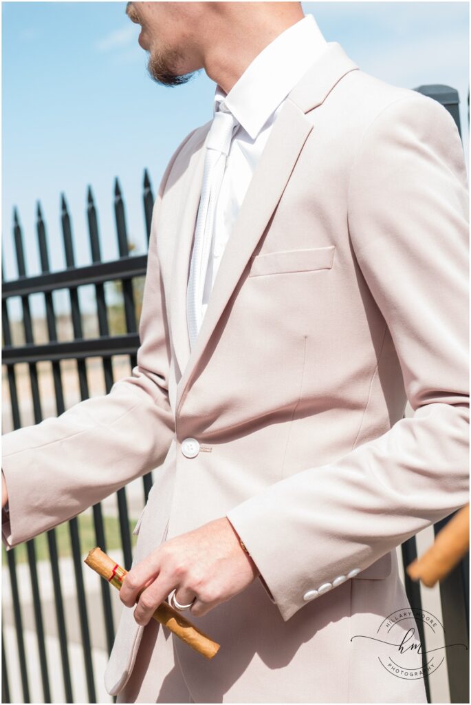 Groom holding an unlit cigar.