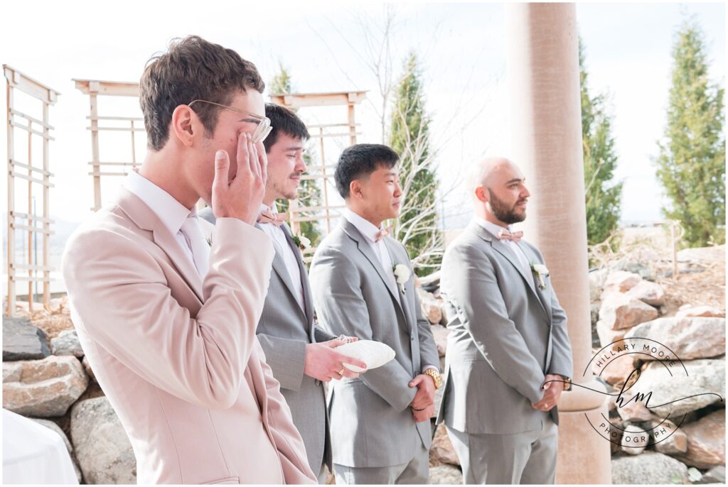 Groom standing with groomsmen watching bride walk down the aisle.