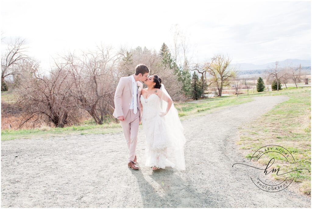 Bride and groom kissing on a gravel road.