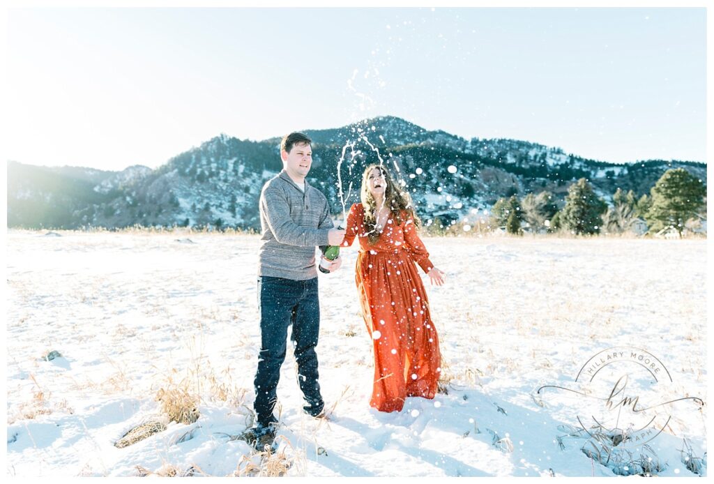 couple opening champagne in field