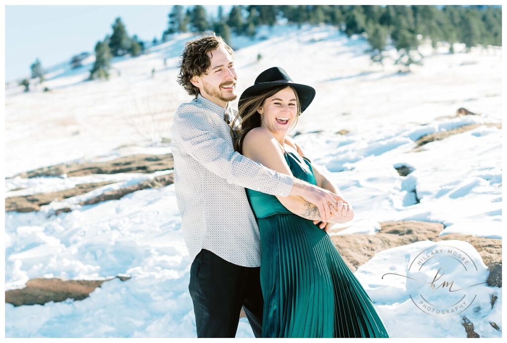 couple laughing in snowy field.