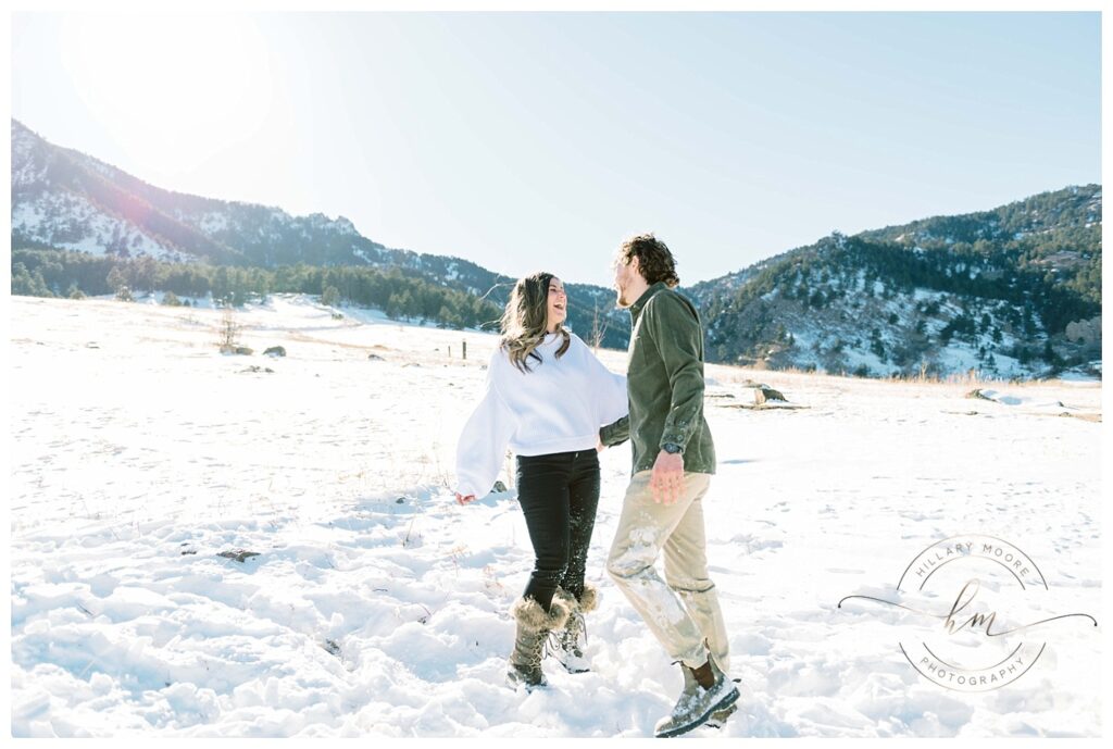 couple smiling and playing in snowy field