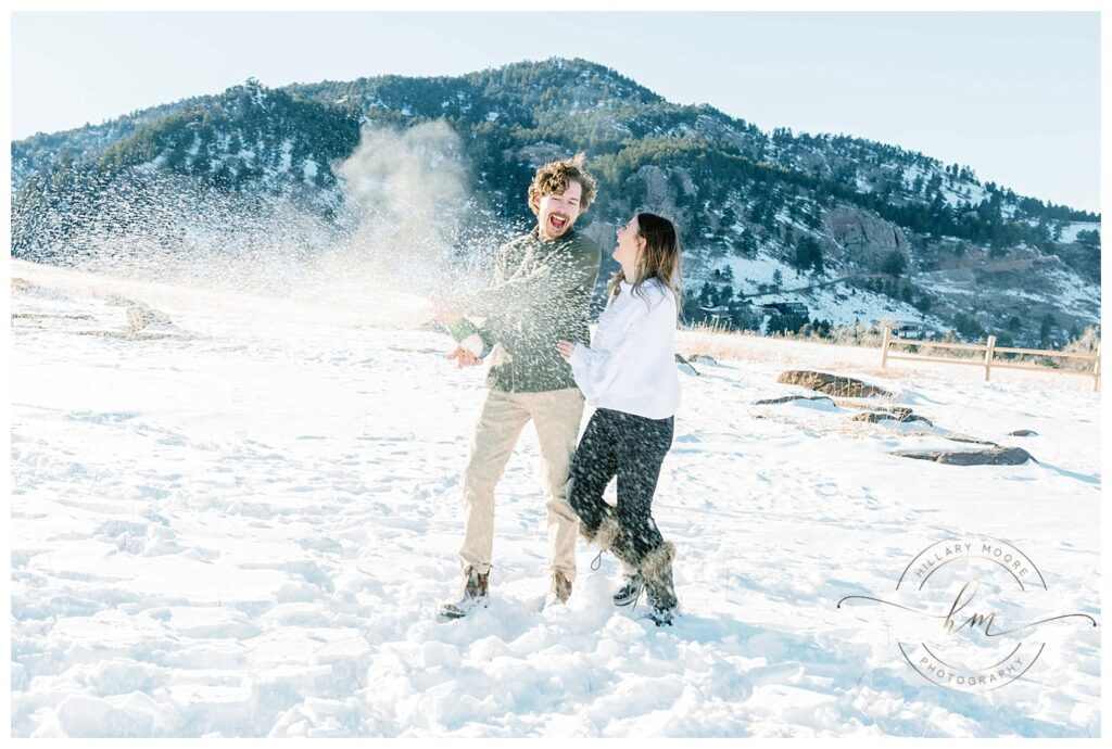 couple playing in snowy field with sun shining