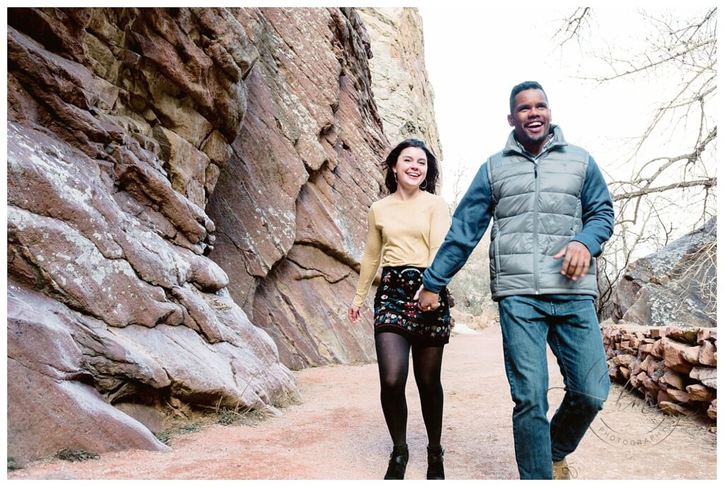 couple walking by rock wall holding hands