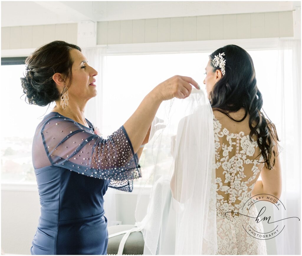 Woman helps bride put on her veil.