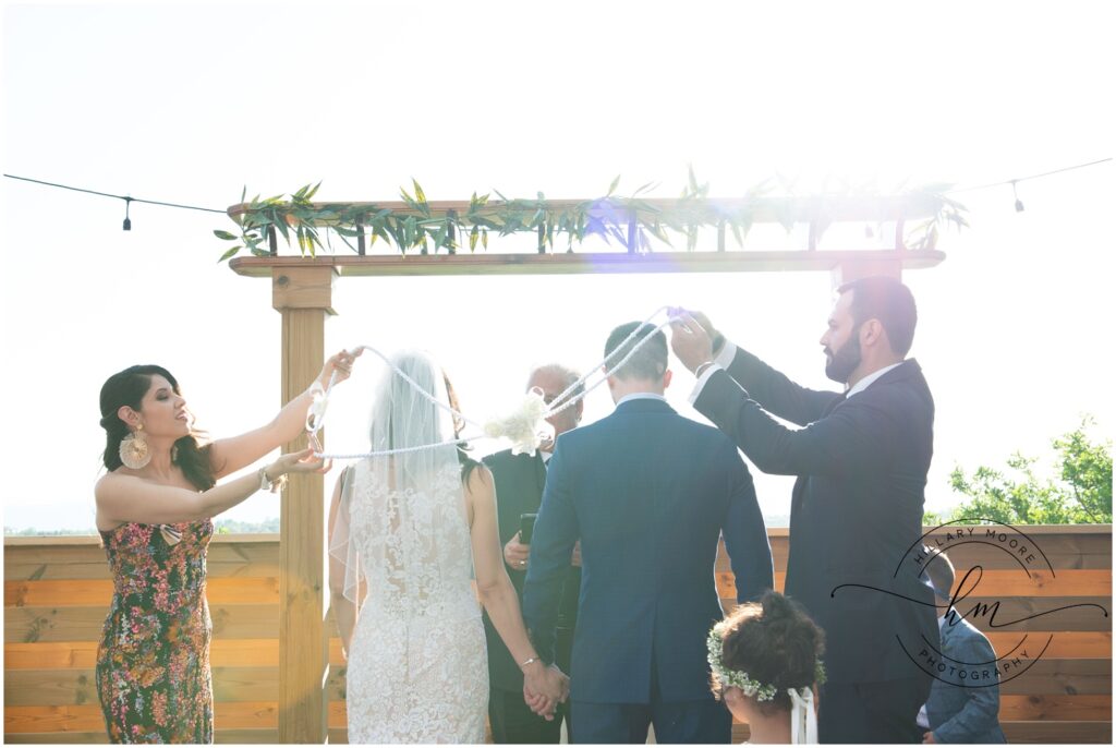 The bride and groom are being roped together at their wedding ceremony.